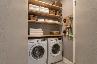 Buanderie compacte avec lave-linge et sèche-linge superposés dans une petite pièce organisée avec étagères et paniers de rangement