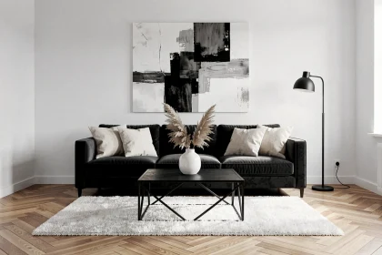 Salon élégant en noir et blanc avec canapé velours anthracite, coussins ivoire, table basse noire et tableau abstrait monochrome sur mur blanc